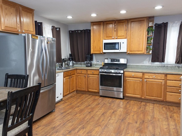 kitchen with stainless steel appliances, recessed lighting, open shelves, and wood finished floors