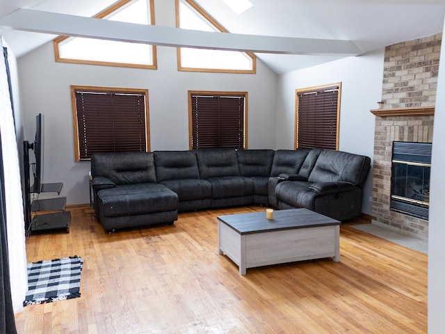 living room featuring lofted ceiling, a fireplace, and light wood finished floors