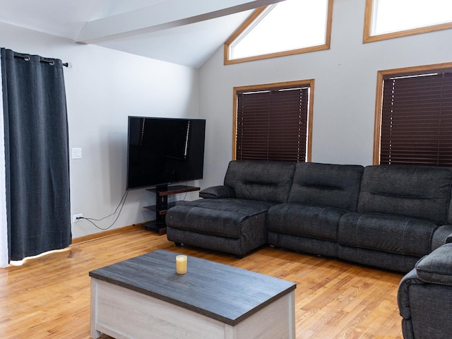 living room with vaulted ceiling with beams, light wood-style flooring, and a wealth of natural light