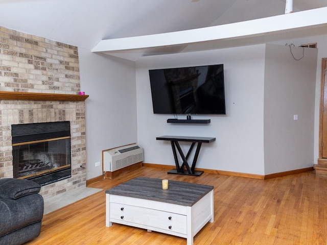 living area featuring vaulted ceiling, a fireplace, wood finished floors, and baseboards