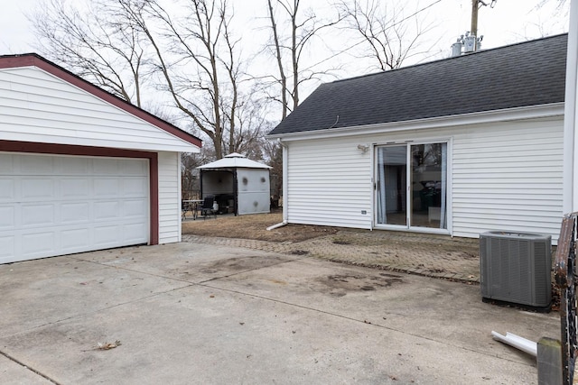 garage with central air condition unit and concrete driveway