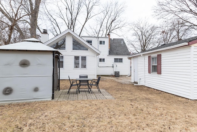 rear view of property with cooling unit, a gazebo, a lawn, a chimney, and a patio area