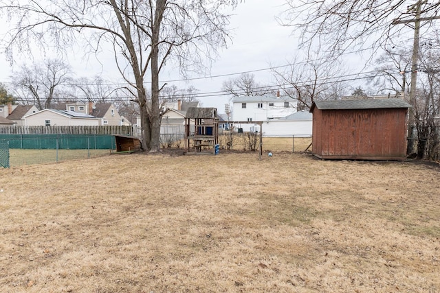 view of yard with a residential view, a storage unit, fence, an outdoor structure, and a playground