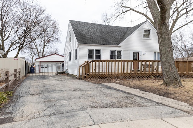 back of property featuring roof with shingles, an outdoor structure, a wooden deck, and fence