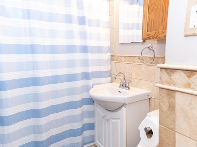 bathroom featuring curtained shower, tile walls, and vanity