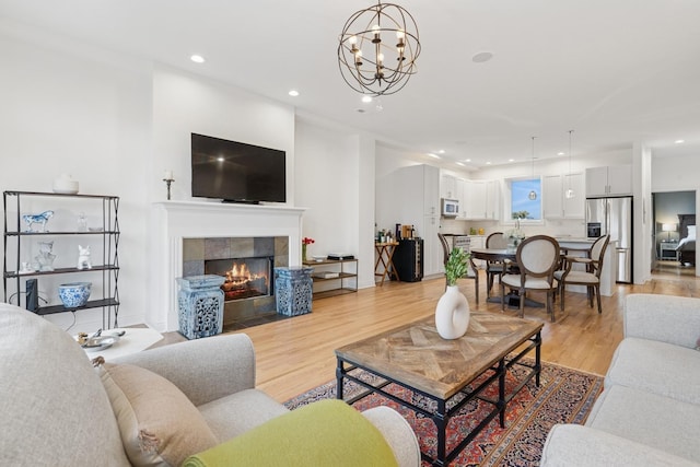 living room with light wood-style floors, a fireplace, baseboards, and recessed lighting