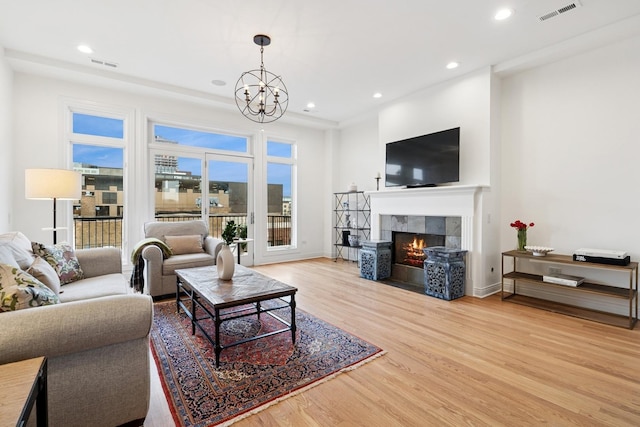 living area featuring a healthy amount of sunlight, light wood-style flooring, visible vents, and a tiled fireplace