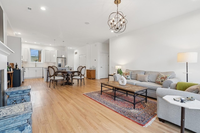 living room with light wood-type flooring, an inviting chandelier, visible vents, and recessed lighting