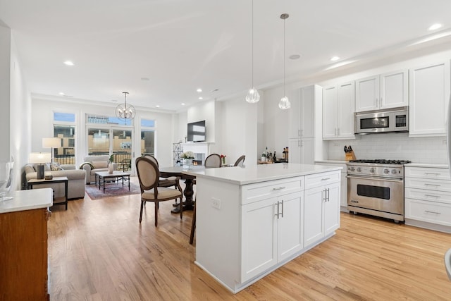 kitchen with open floor plan, light countertops, appliances with stainless steel finishes, light wood finished floors, and tasteful backsplash