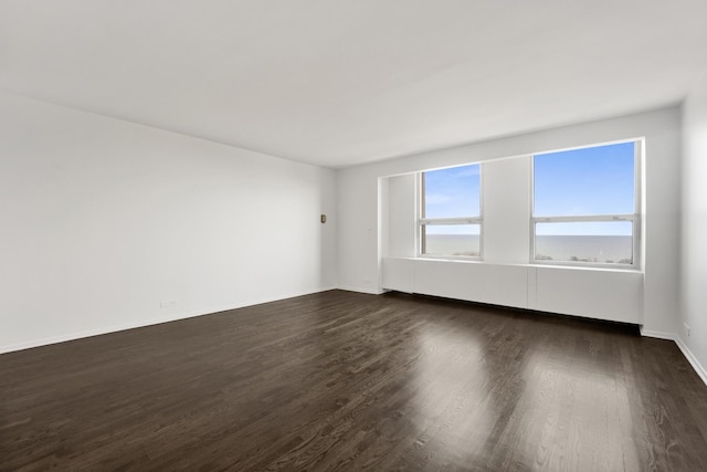 spare room with dark wood-style flooring and baseboards