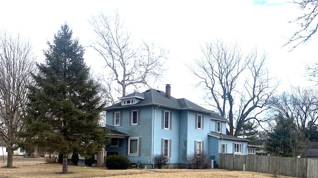 view of side of property with a chimney and fence