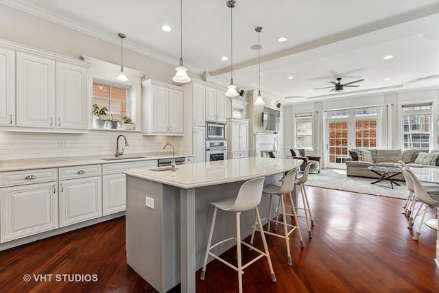 1307 W Wellington Ave, Chicago, IL 60657 - kitchen featuring a sink, appliances with stainless steel finishes, a ceiling fan, crown molding, and an island with sink