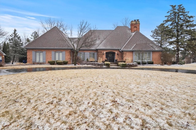 view of front of property with a shingled roof, a chimney, and brick siding