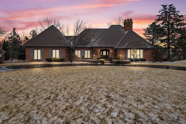 view of front of home featuring brick siding and a chimney