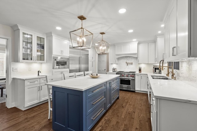 kitchen with premium appliances, white cabinetry, a sink, a kitchen island, and premium range hood