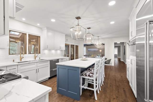 kitchen with a kitchen island, appliances with stainless steel finishes, white cabinets, and a sink