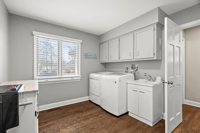 clothes washing area with a sink, baseboards, washer and dryer, cabinet space, and dark wood finished floors