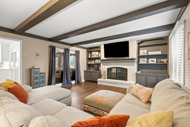 living room featuring a brick fireplace, beam ceiling, built in features, and dark wood-style flooring