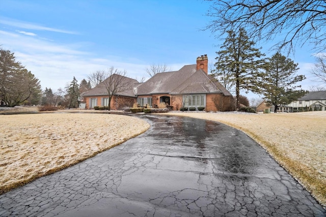 view of front facade featuring driveway and a chimney