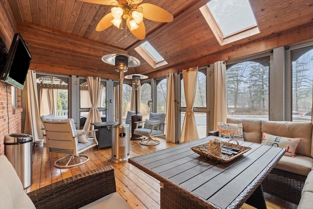 sunroom with vaulted ceiling with skylight, wooden ceiling, and ceiling fan