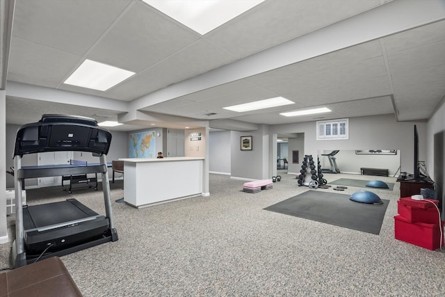 exercise room featuring a drop ceiling and baseboards