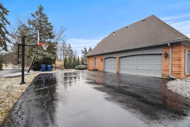 view of home's exterior with roof with shingles, aphalt driveway, and brick siding