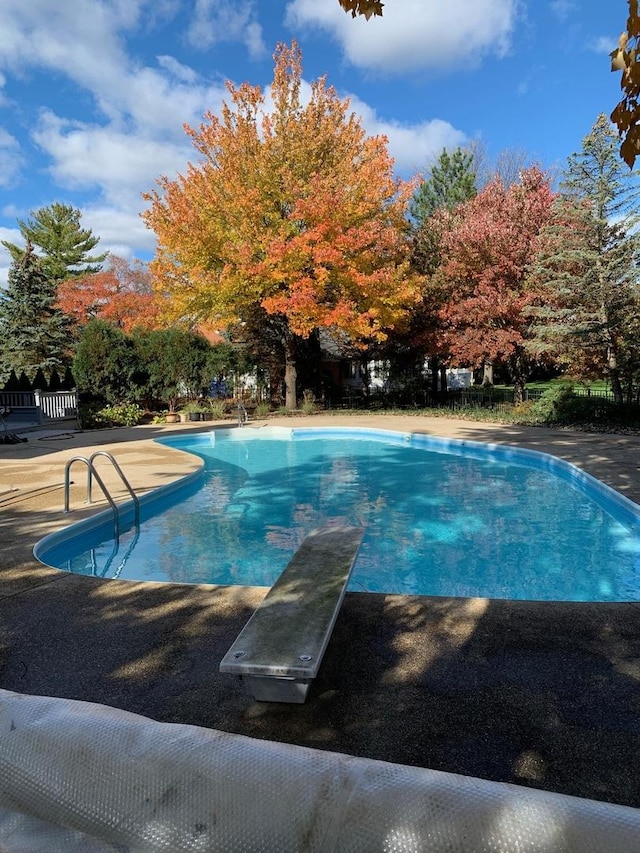 outdoor pool featuring a diving board and a patio