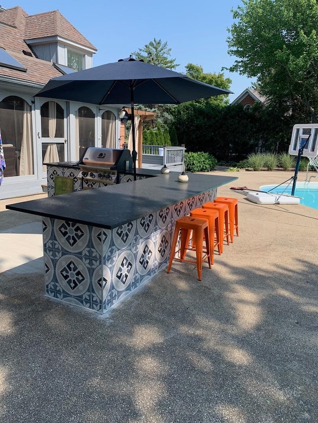 view of patio with an outdoor pool, outdoor dry bar, and area for grilling