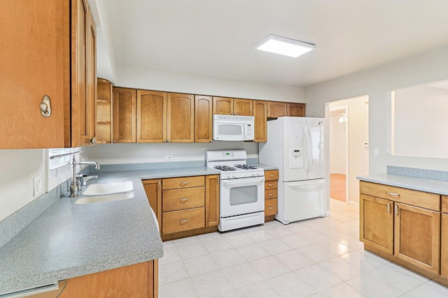 kitchen with light countertops, white appliances, brown cabinetry, and a sink