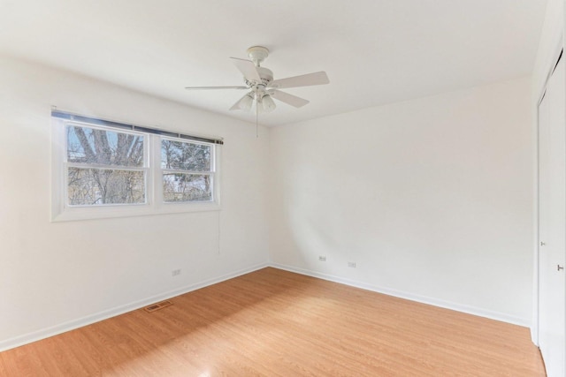 empty room with baseboards, ceiling fan, visible vents, and light wood-style floors