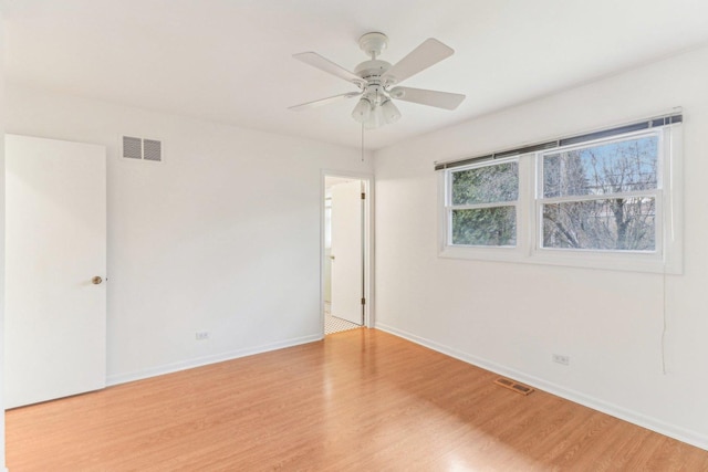 empty room featuring a ceiling fan, light wood-style flooring, visible vents, and baseboards