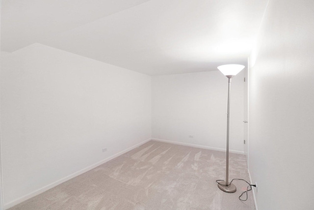 spare room with light carpet and baseboards