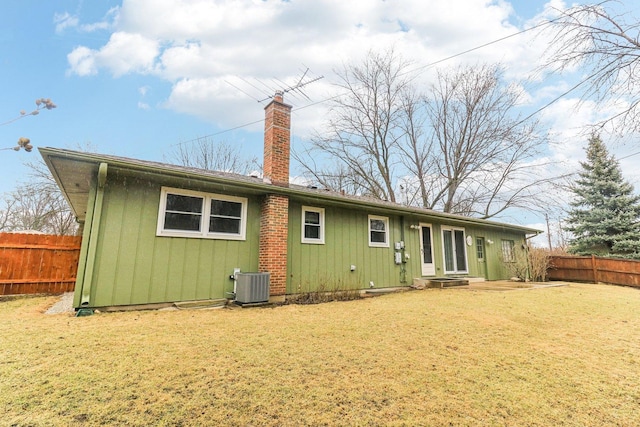 back of house with central AC unit, a chimney, fence, and a lawn