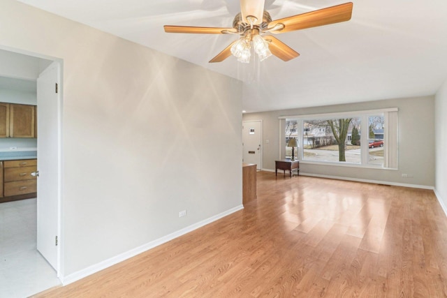 spare room with a ceiling fan, baseboards, and light wood finished floors