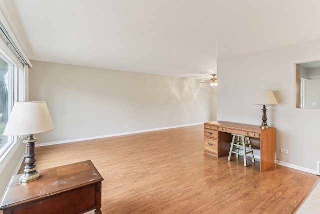 office area with light wood-style floors, ceiling fan, and baseboards