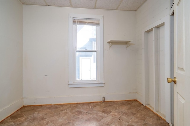 unfurnished room featuring a paneled ceiling and baseboards