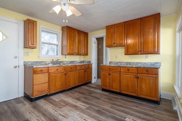 kitchen with a sink, ceiling fan, brown cabinets, and dark wood-type flooring