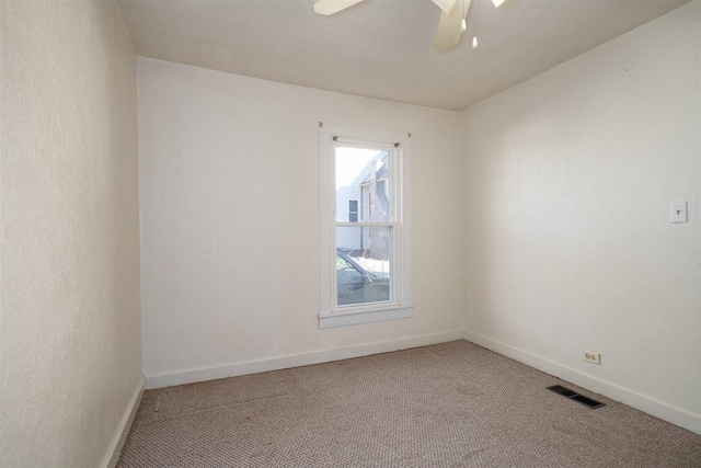 empty room featuring carpet floors, baseboards, visible vents, and ceiling fan