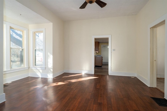 empty room with a ceiling fan, visible vents, baseboards, and wood finished floors