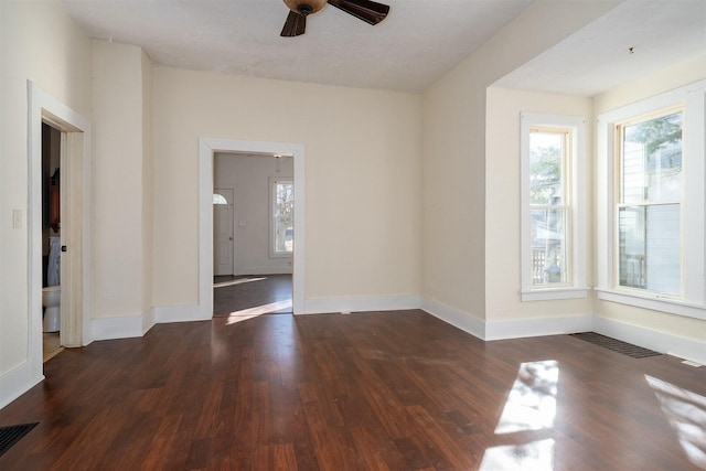 empty room with a wealth of natural light, visible vents, and wood finished floors