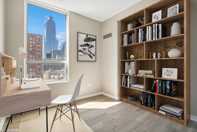 office area featuring a view of city, wood finished floors, visible vents, and baseboards