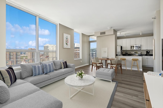 living area featuring visible vents, a view of city, baseboards, and dark wood-type flooring