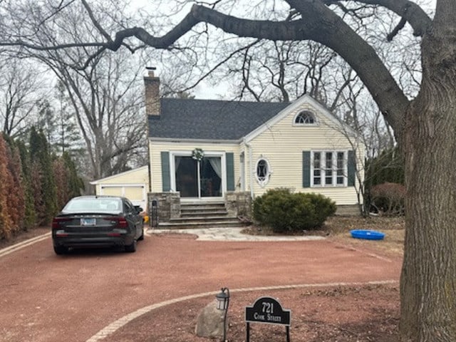 view of front of property featuring driveway, a chimney, and entry steps