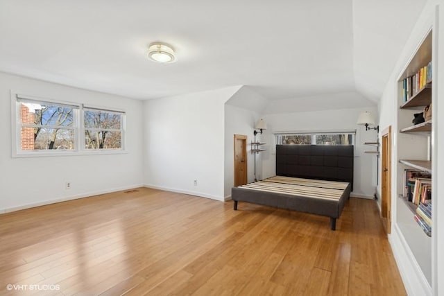 bedroom featuring lofted ceiling, light wood-style flooring, and baseboards