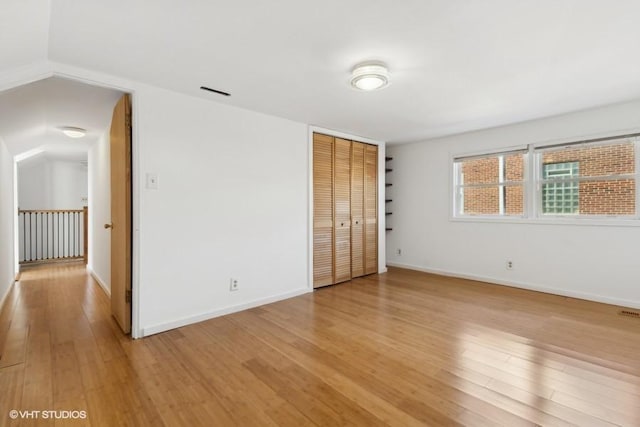 unfurnished bedroom with a closet, baseboards, visible vents, and light wood finished floors