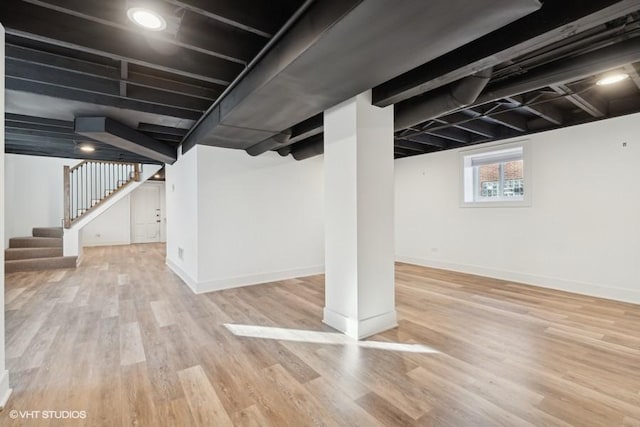 below grade area featuring stairway, wood finished floors, and baseboards