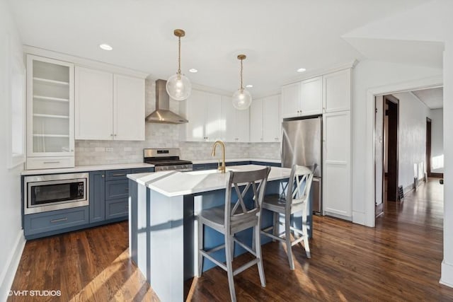 kitchen featuring stainless steel appliances, wall chimney exhaust hood, light countertops, and white cabinetry