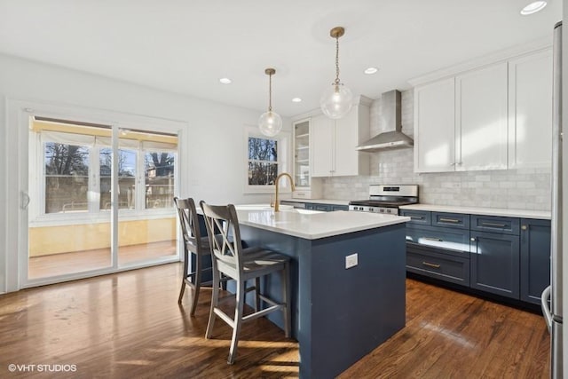 kitchen featuring wall chimney range hood, stainless steel electric range, white cabinets, and decorative backsplash