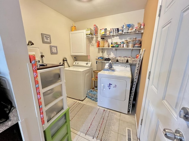 laundry room featuring light tile patterned flooring, cabinet space, visible vents, and separate washer and dryer