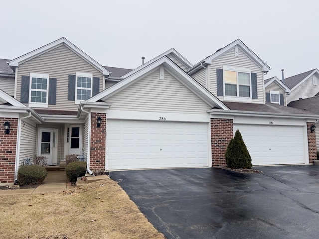 traditional-style home featuring brick siding, driveway, and an attached garage